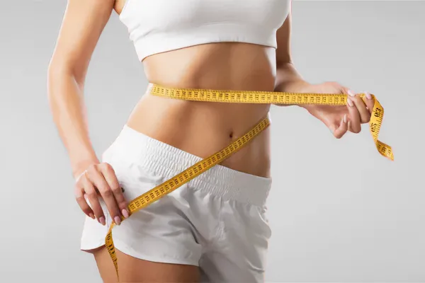 LowTE-Skinny-Shot-Clinic A woman holds a measuring tape around her waist to show weight loss. Get the LowTE Skinny Shot from Carolyn Zaumeyer, MSN, APRN in Fort Lauderdale.
