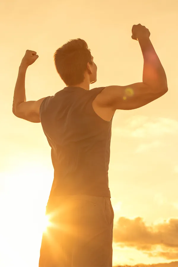 A fit man flexes his arms in the sunset. Get a consultation about the THINNR Weight Loss Program from Carolyn Zaumeyer, MSN, APRN at LowTE Florida® in Greater Fort Lauderdale.