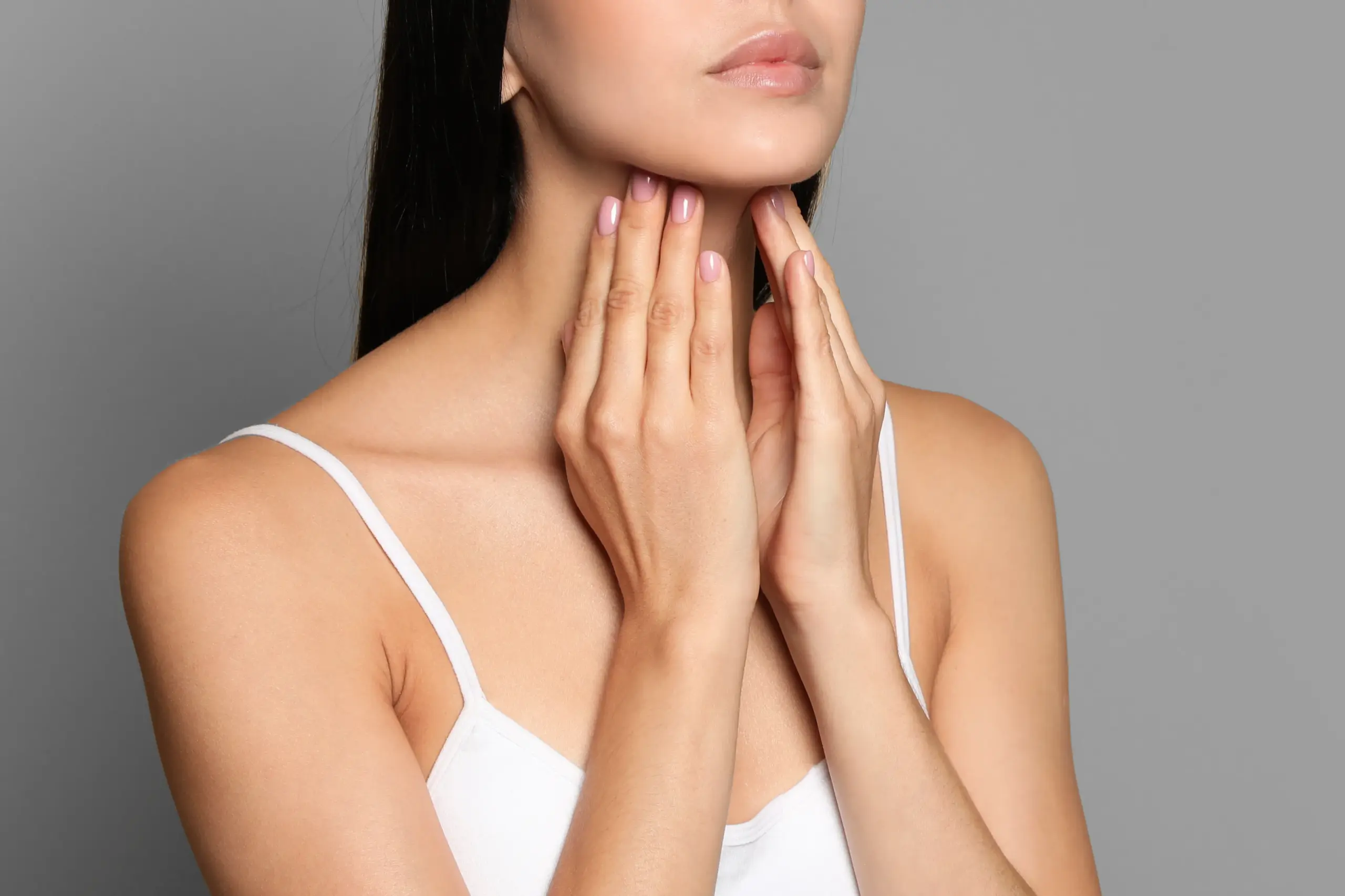 A woman in a white tank top touches her neck looking for signs of thyroid disorder. Get help for thyroid disorders from Carolyn Zaumeyer, MSN, APRN at LowTE Florida® in Greater Fort Lauderdale.
