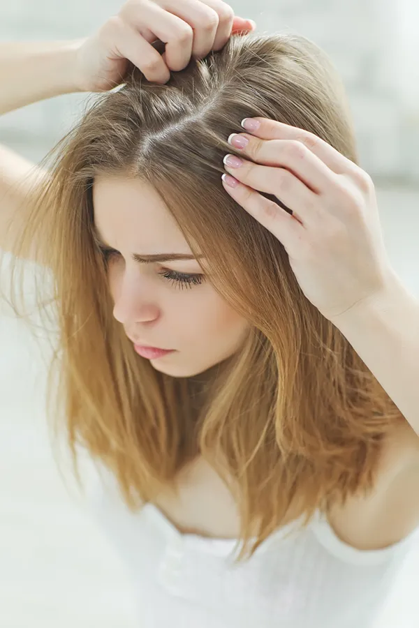 Viviscal-for-Womens-Hair-Loss-Treatment A brown-haired woman checks her scalp for thinning hair. Get Viviscal for women's hair restoration from Carolyn Zaumeyer, MSN, APRN in Fort Lauderdale.