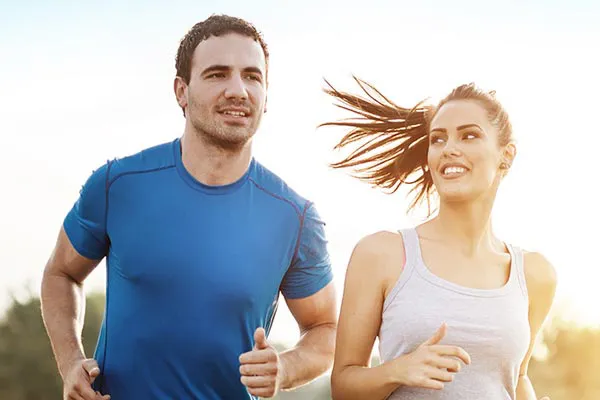 A couple happily jogging in the sunlight after receiving effective weight loss resistance care from Carolyn Zaumeyer, MSN, APRN at LowTE Florida® in Greater Fort Lauderdale.